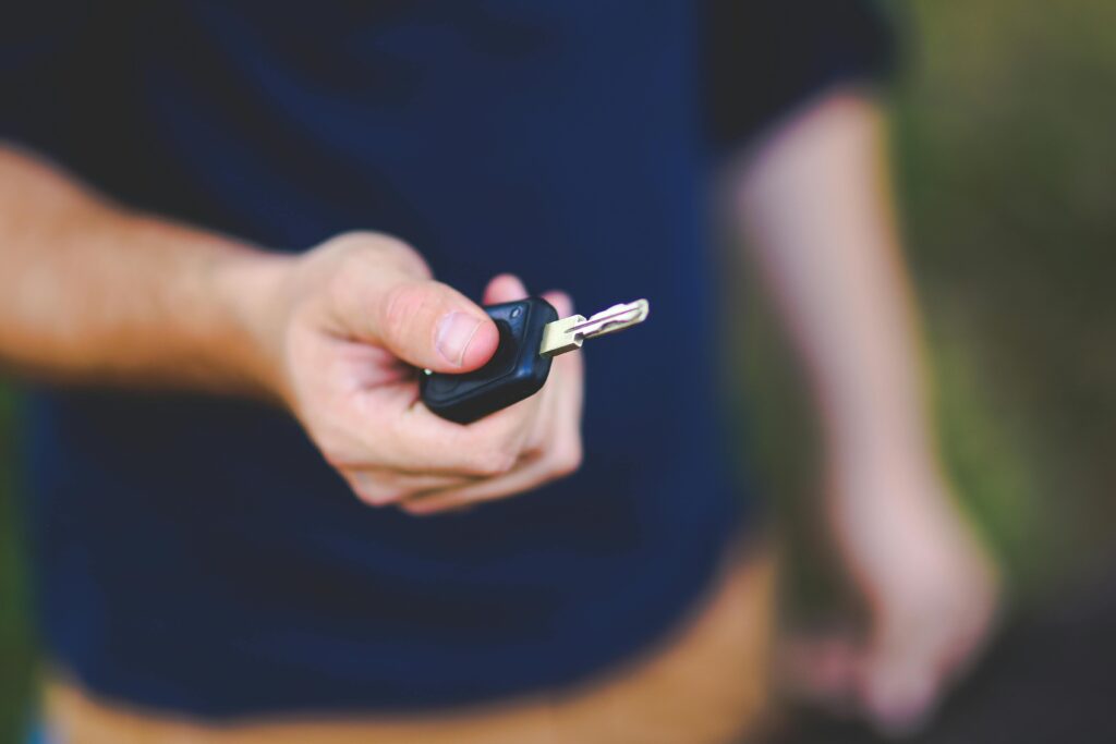A hand holding a car key outdoors, emphasizing security and control.