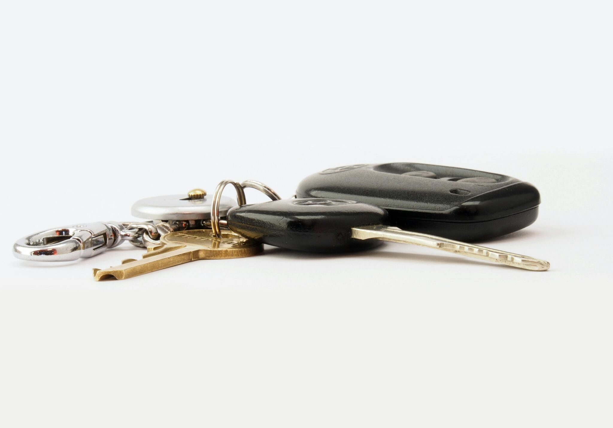 Detailed image of car keys on a white surface, including a key fob and keychain.