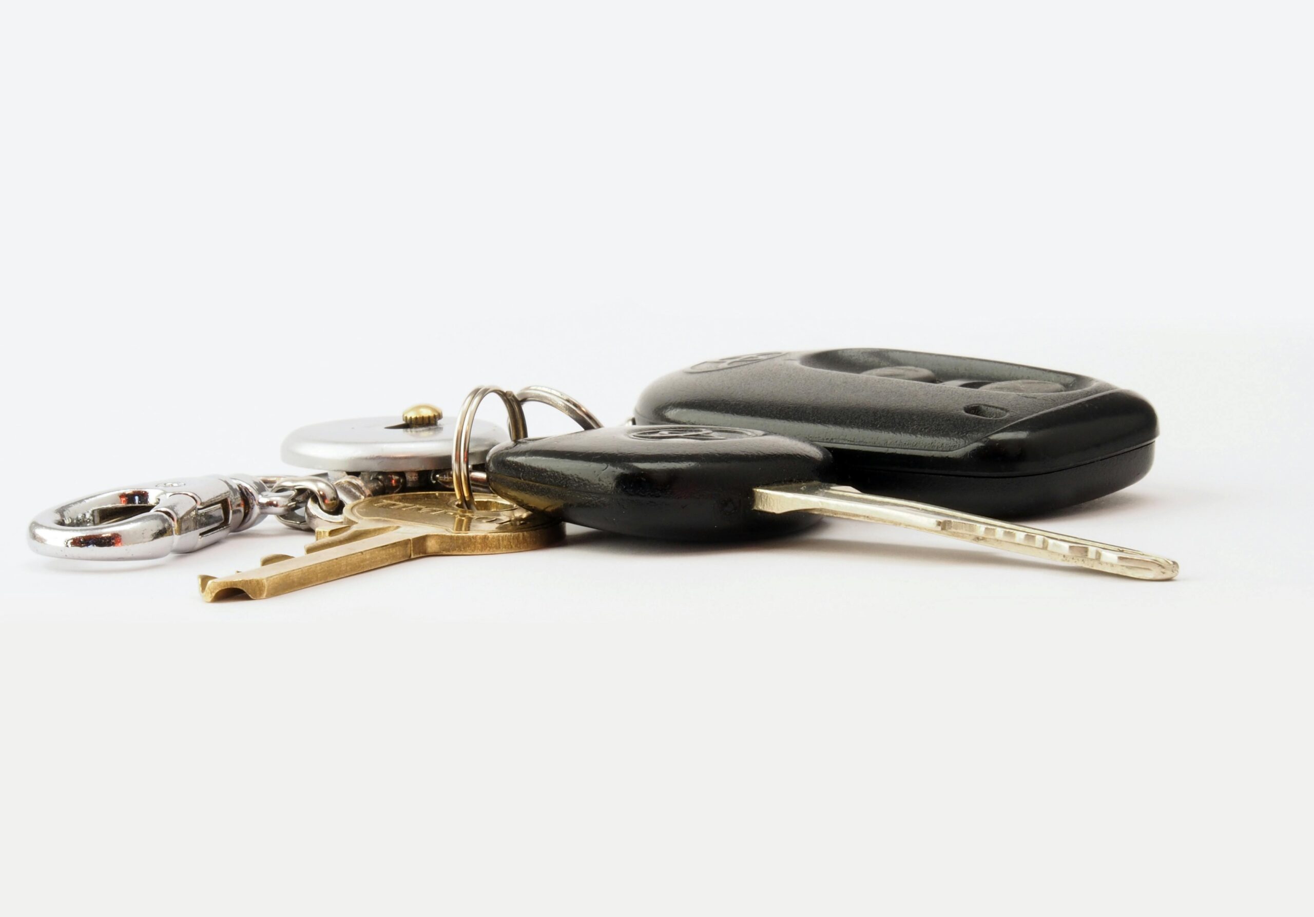 Detailed image of car keys on a white surface, including a key fob and keychain.