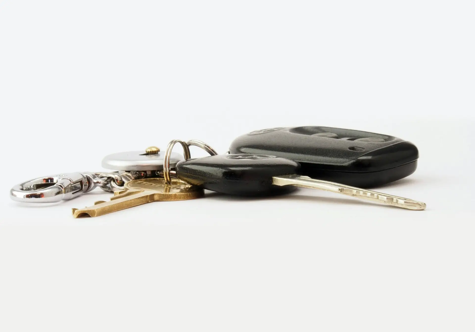 Detailed image of car keys on a white surface, including a key fob and keychain.